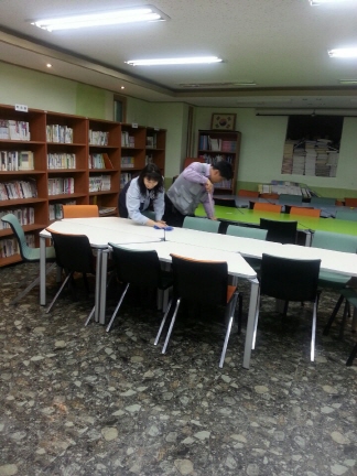 책상을 청소중인 봉사단원과 책상바닥을 청소중인 봉사단원