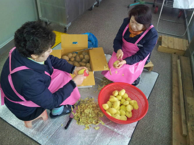 울산지점 나누리 봉사단 중 2명이 감자를 깍고있는 사진