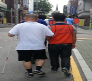새빛맹인선교원 맹인들과 짝을 이루어 길을 걷고있는 봉사단 사진